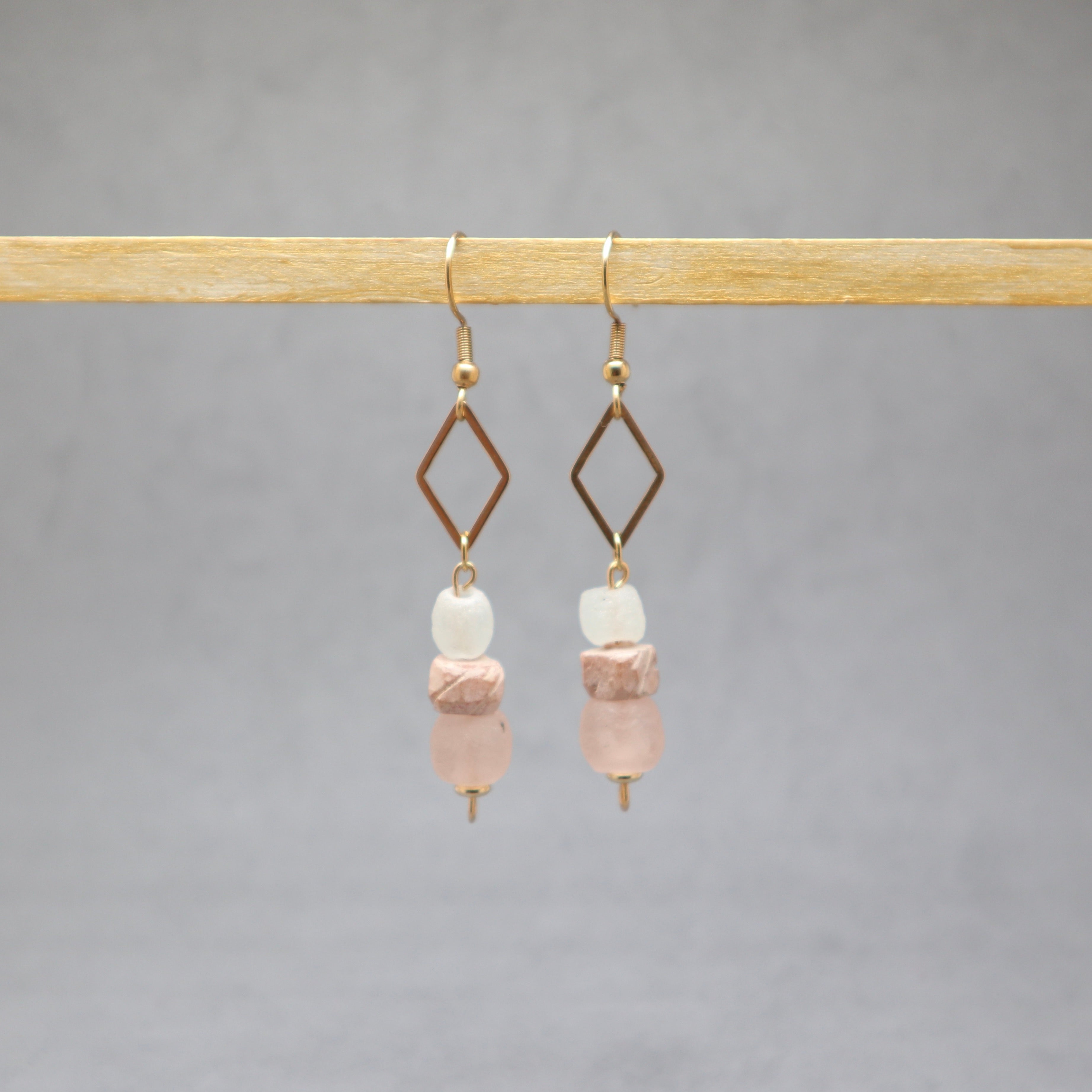 Pair of earrings with pink and white beads on a gray background, stainless steel, bone, recycled glass
