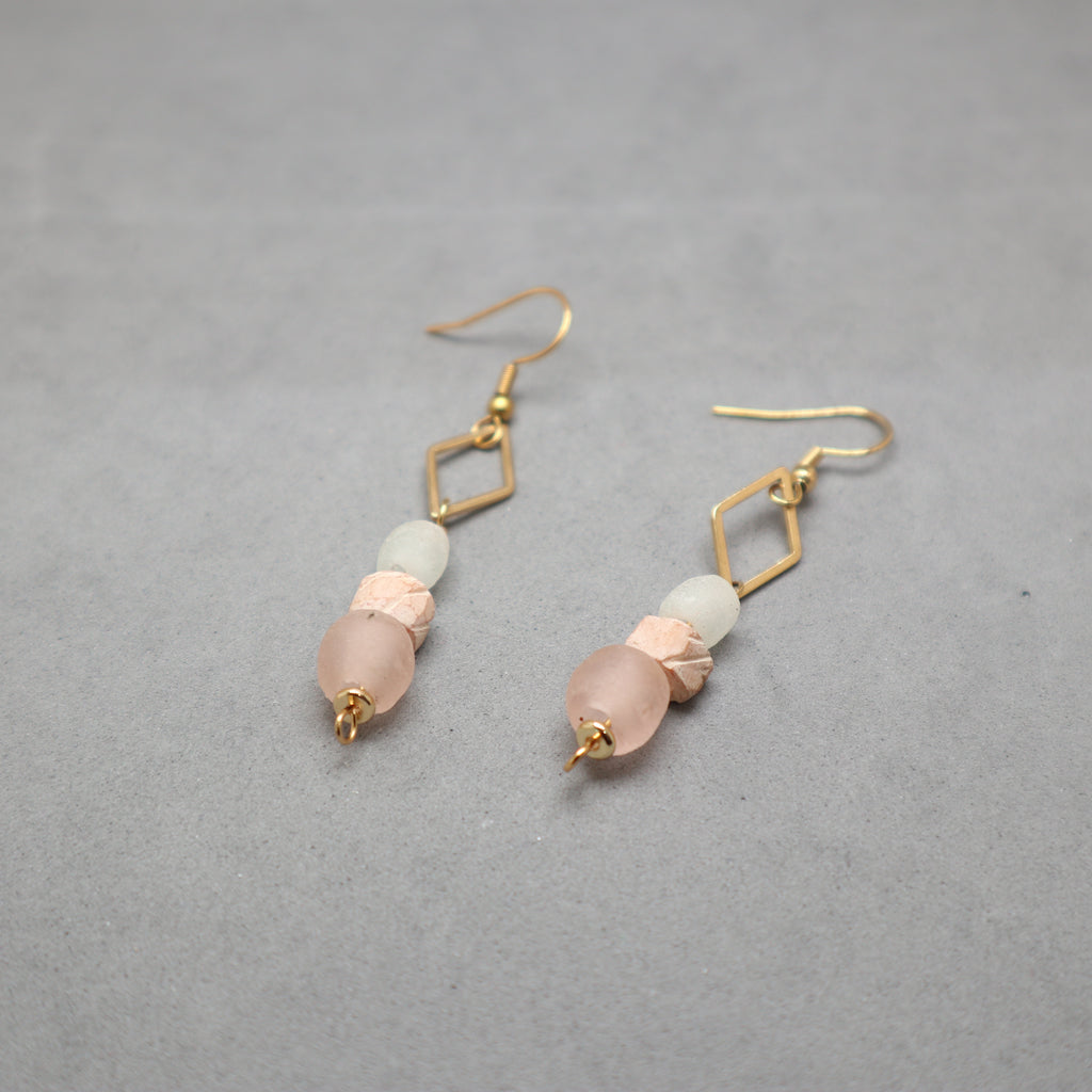 Pair of earrings with pink and gold accents on a gray background