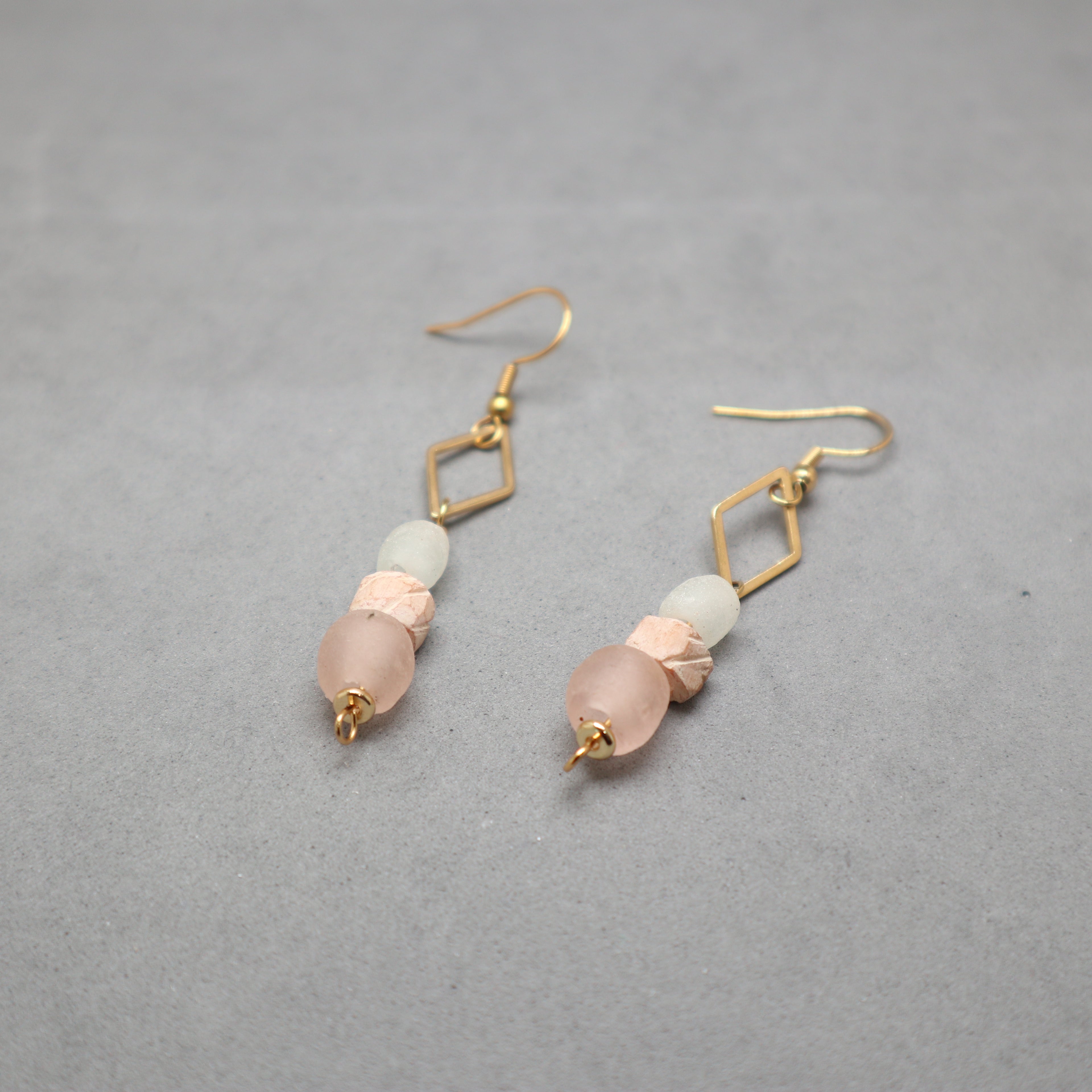 Pair of earrings with pink and gold accents on a gray background