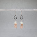 Pair of earrings with diamond-shaped elements and pink and white beads on a gray background, recycled glass, bone and stainless steel silver