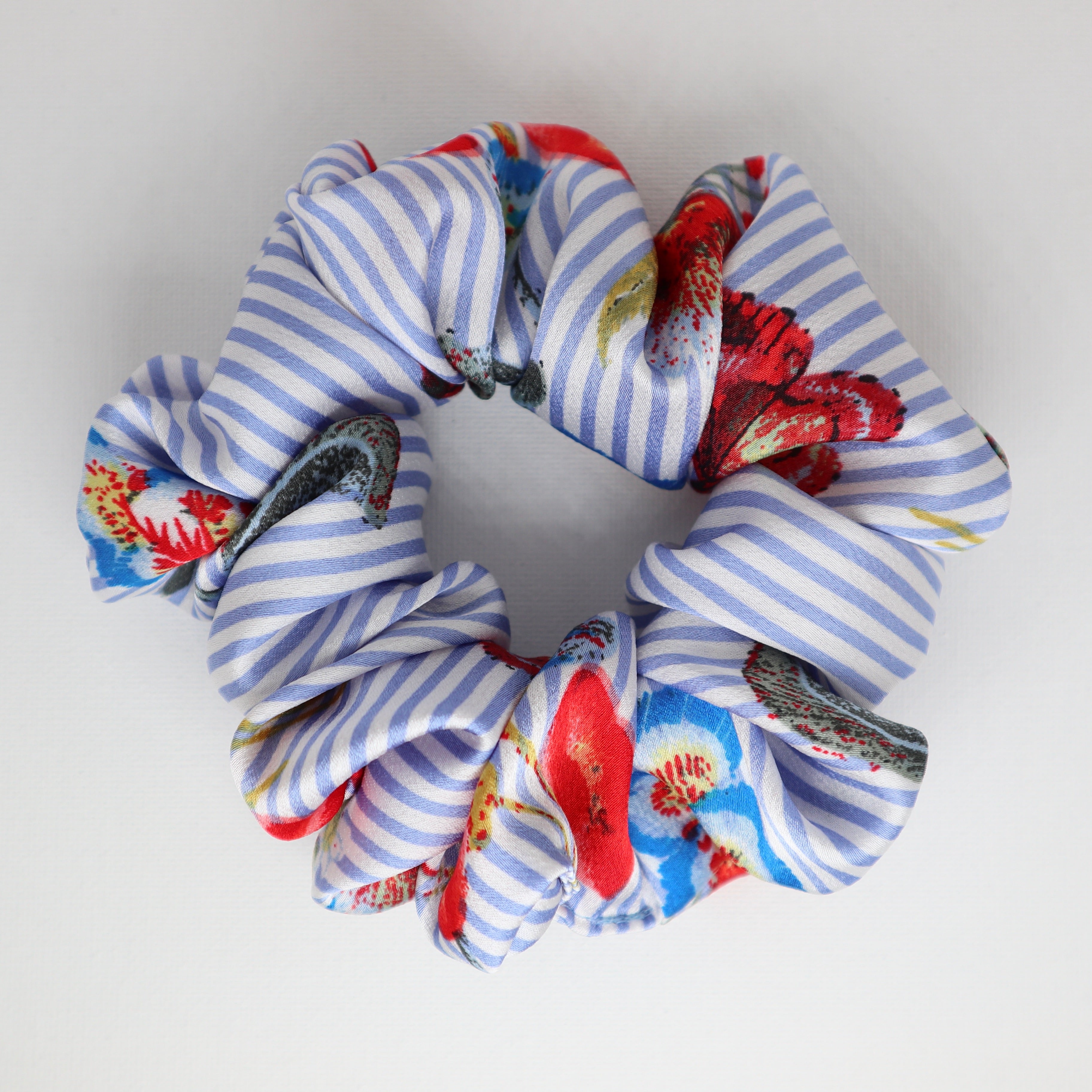 Blue and white striped scrunchie with floral patterns on a white background