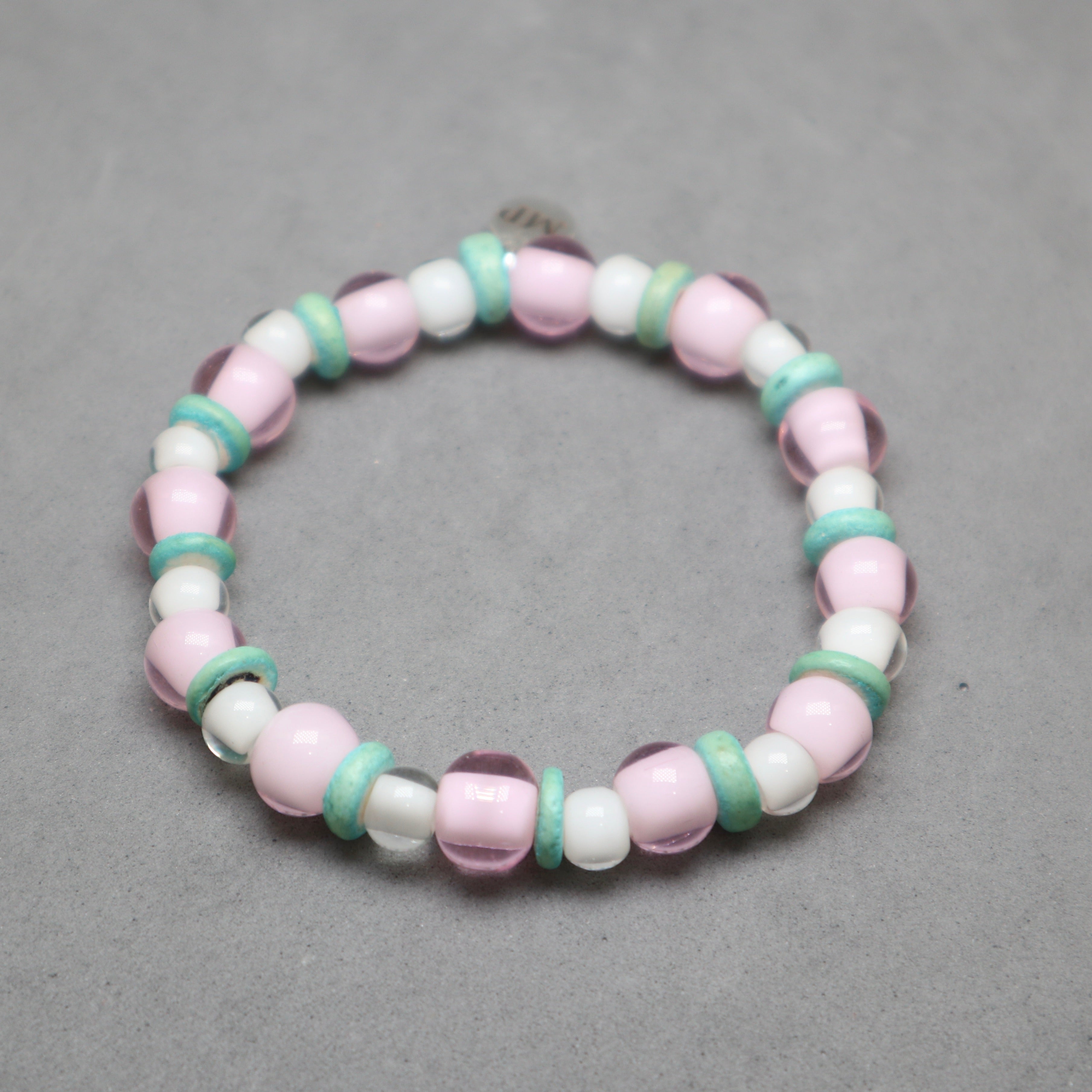 Beaded bracelet with pink, white, and green beads on a gray background