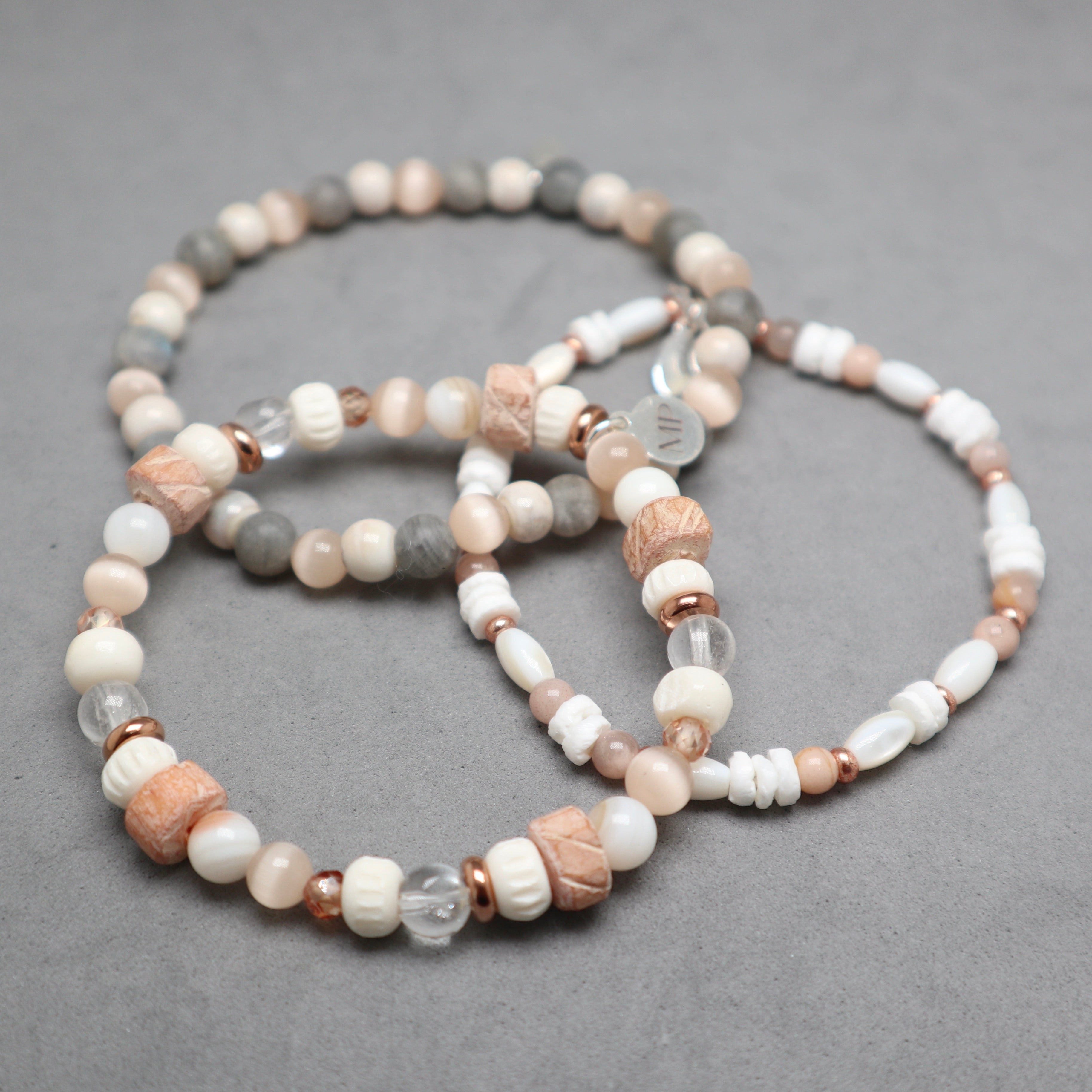 Set of beaded bracelets on a gray surface, bon, quartz, eye cat's beds, shell, moonstone, labradorite, ceramic, stainless steel
