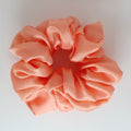 Peach-colored scrunchie on a light gray background