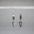 Pair of earrings with beaded elements and arrowhead shapes on a gray background, red and green paper beads from Ouganda with stainless steel. 