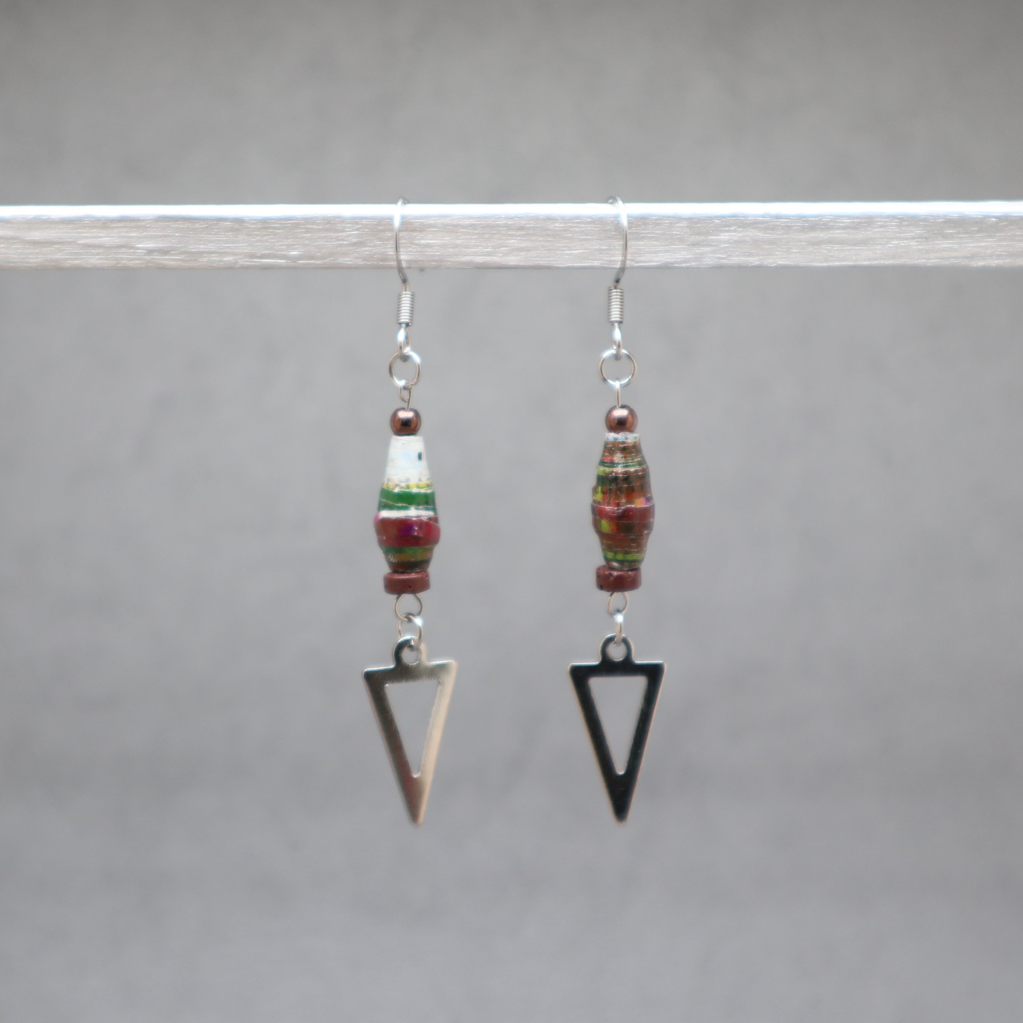 Pair of earrings with beaded elements and arrowhead shapes on a gray background, red and green paper beads from Ouganda with stainless steel. 