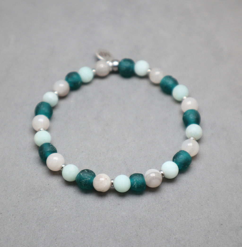 Beaded bracelet with green, white, and pink beads on a gray background, agate, recycled glass teal, amazonite, stainless steel