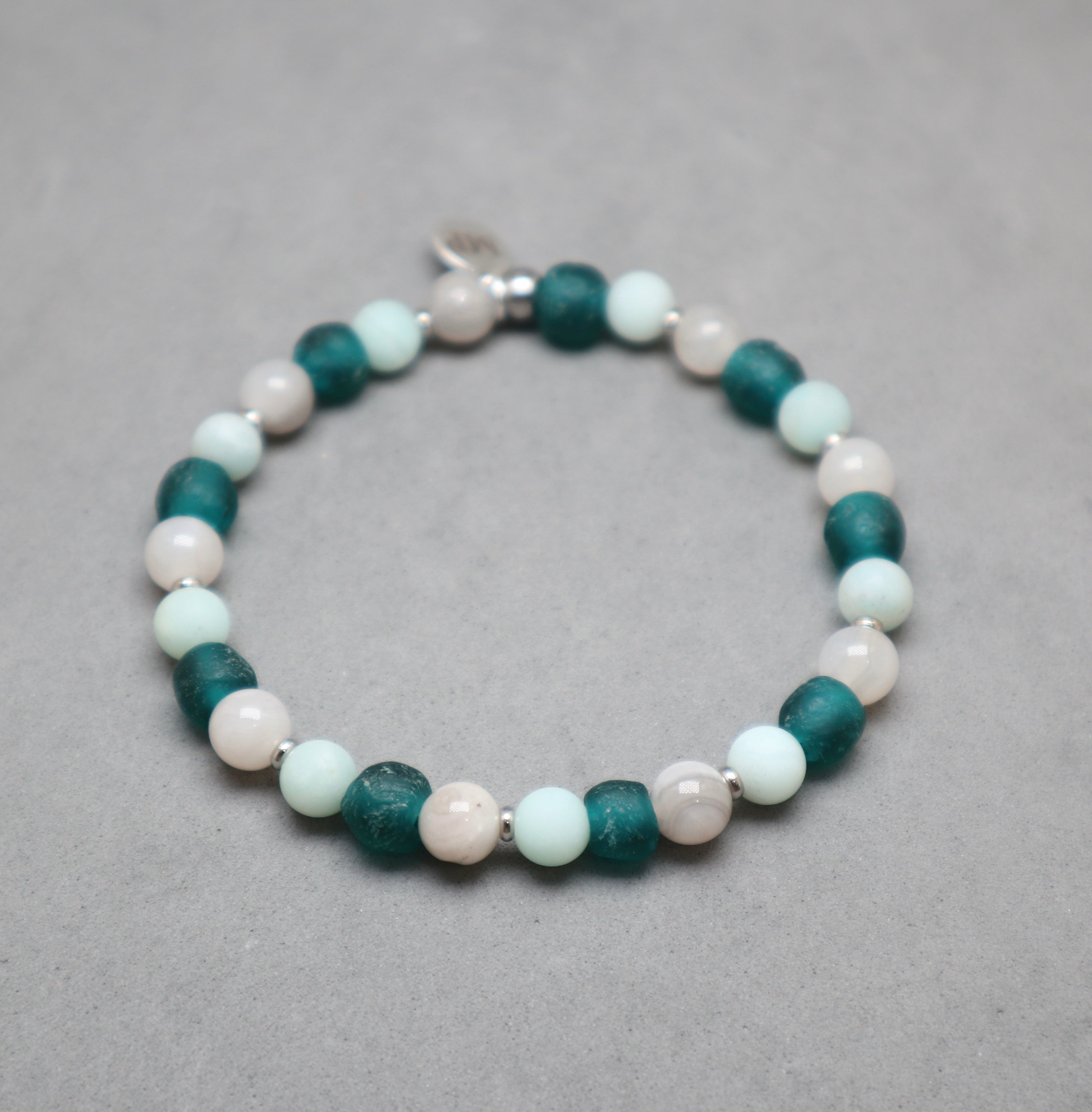 Beaded bracelet with green, white, and pink beads on a gray background, agate, recycled glass teal, amazonite, stainless steel