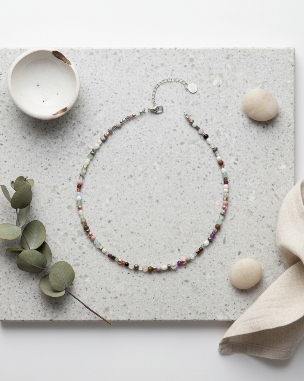 Beaded necklace on a textured surface with decorative elements, green, rose gold, hematite