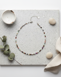 Beaded necklace on a textured surface with decorative elements, green, rose gold, hematite