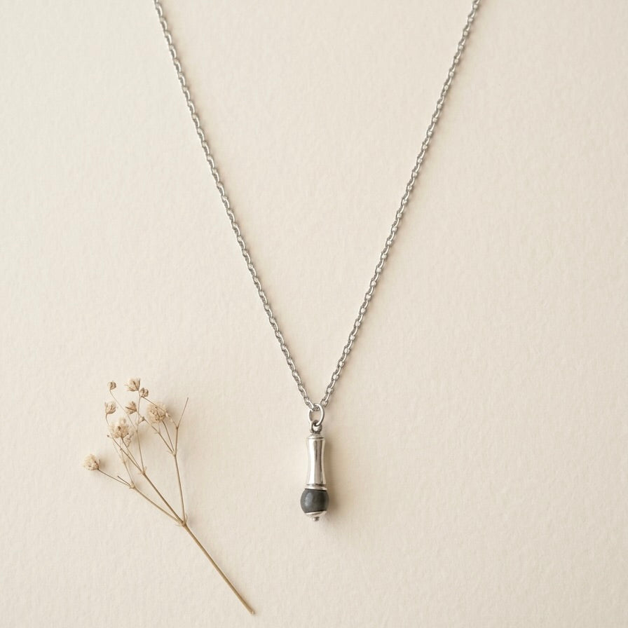 flay laay of a stainless steel necklace with recycled glass bead charcoal and a bamboo meal piece