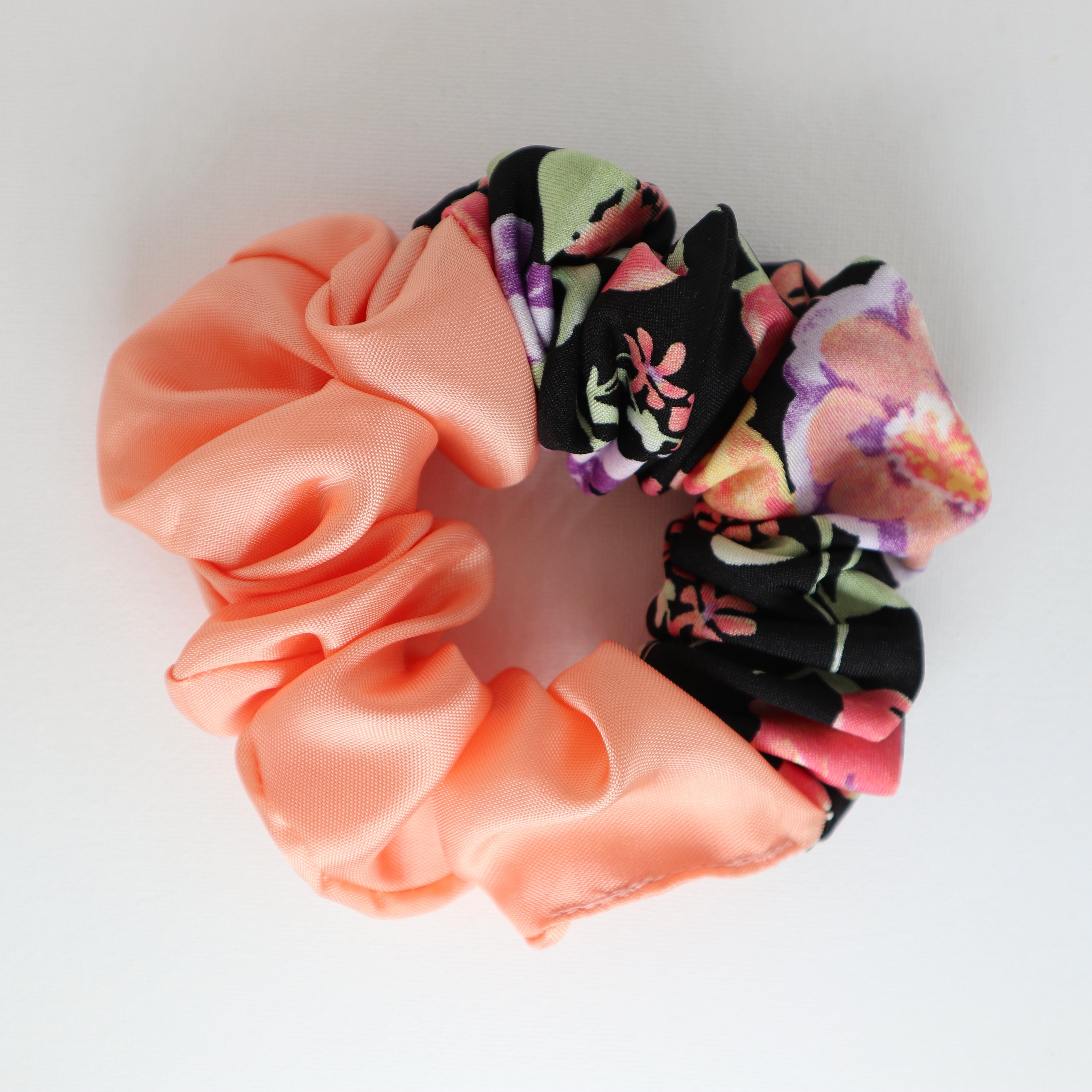 Two fabric scrunchies, one peach and one floral, on a white background