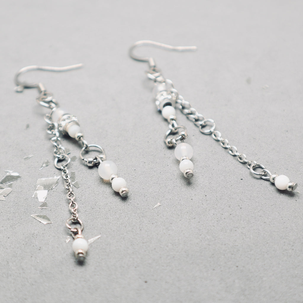 Silver earrings with beads on a gray surface