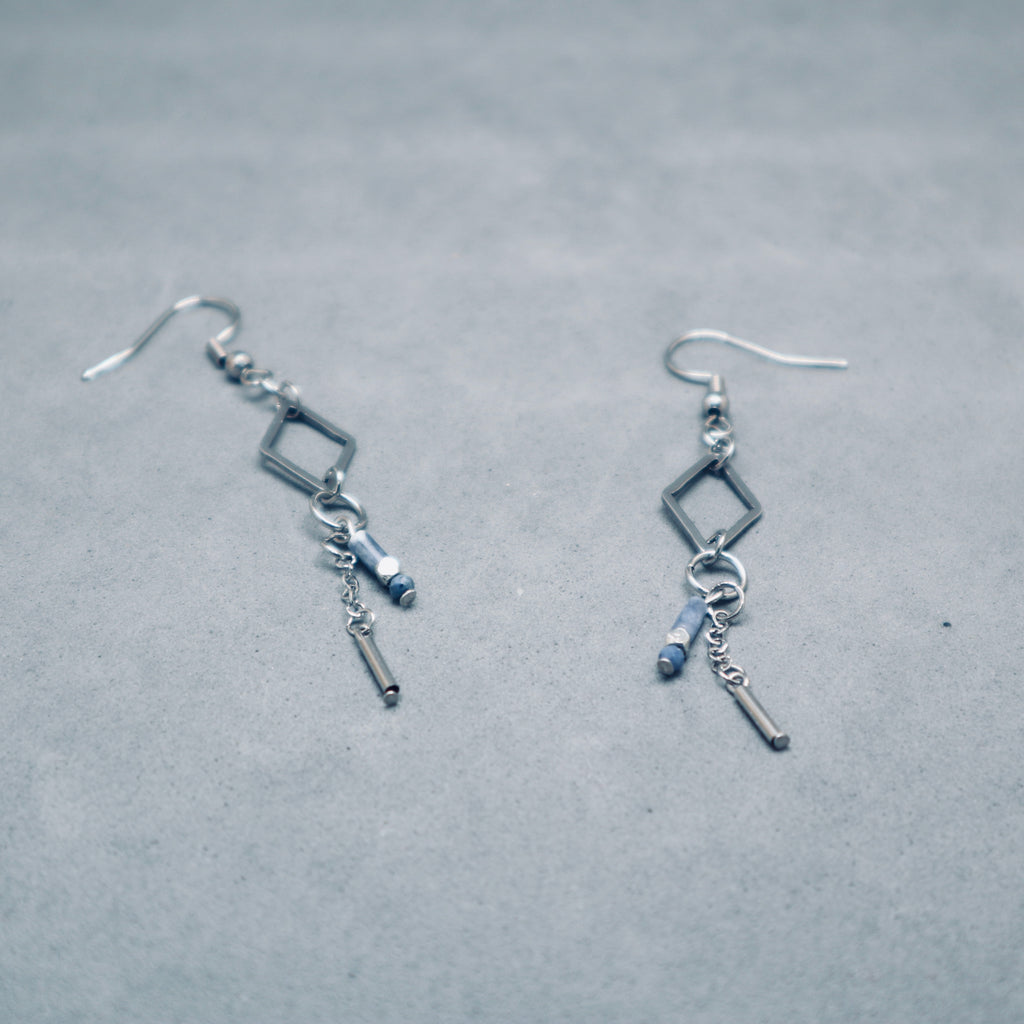 Pair of silver earrings with square and bar charms on a gray background,Stainless steel silver diamond shape with sodalite blue gemstone and metal