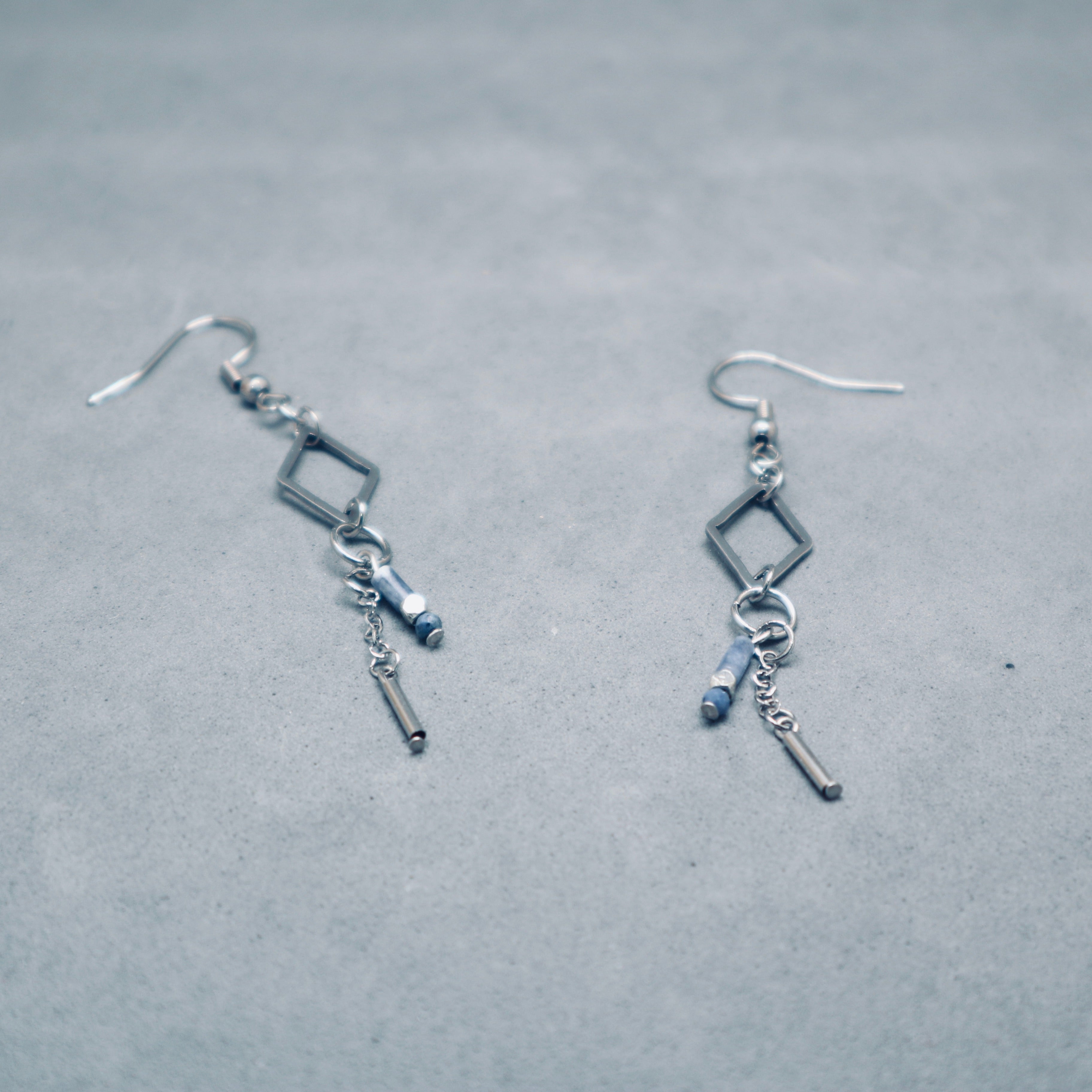 Pair of silver earrings with square and bar charms on a gray background,Stainless steel silver diamond shape with sodalite blue gemstone and metal